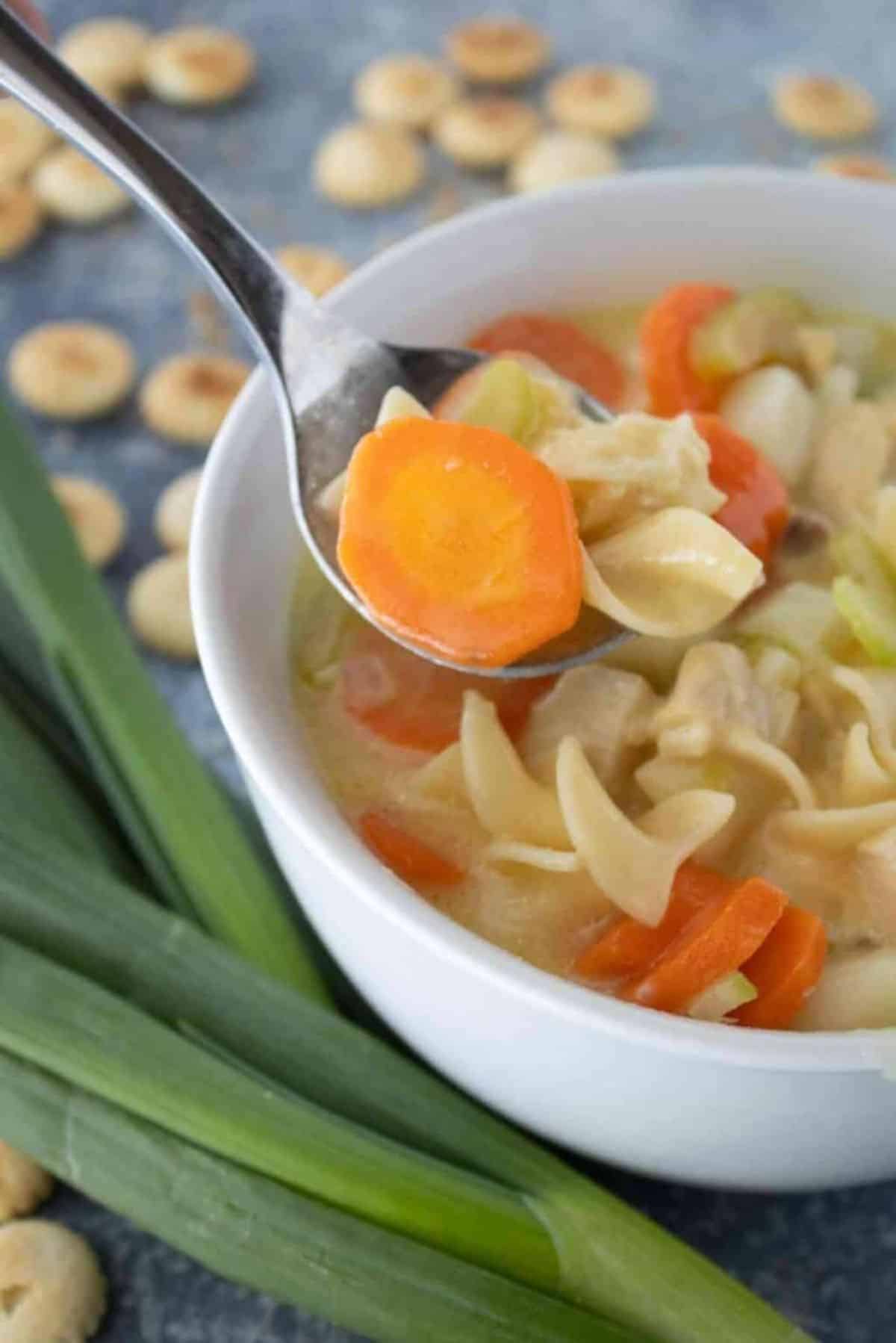 Healthy Creamy Chicken Noodle Soup in a white bowl and on a spoon.