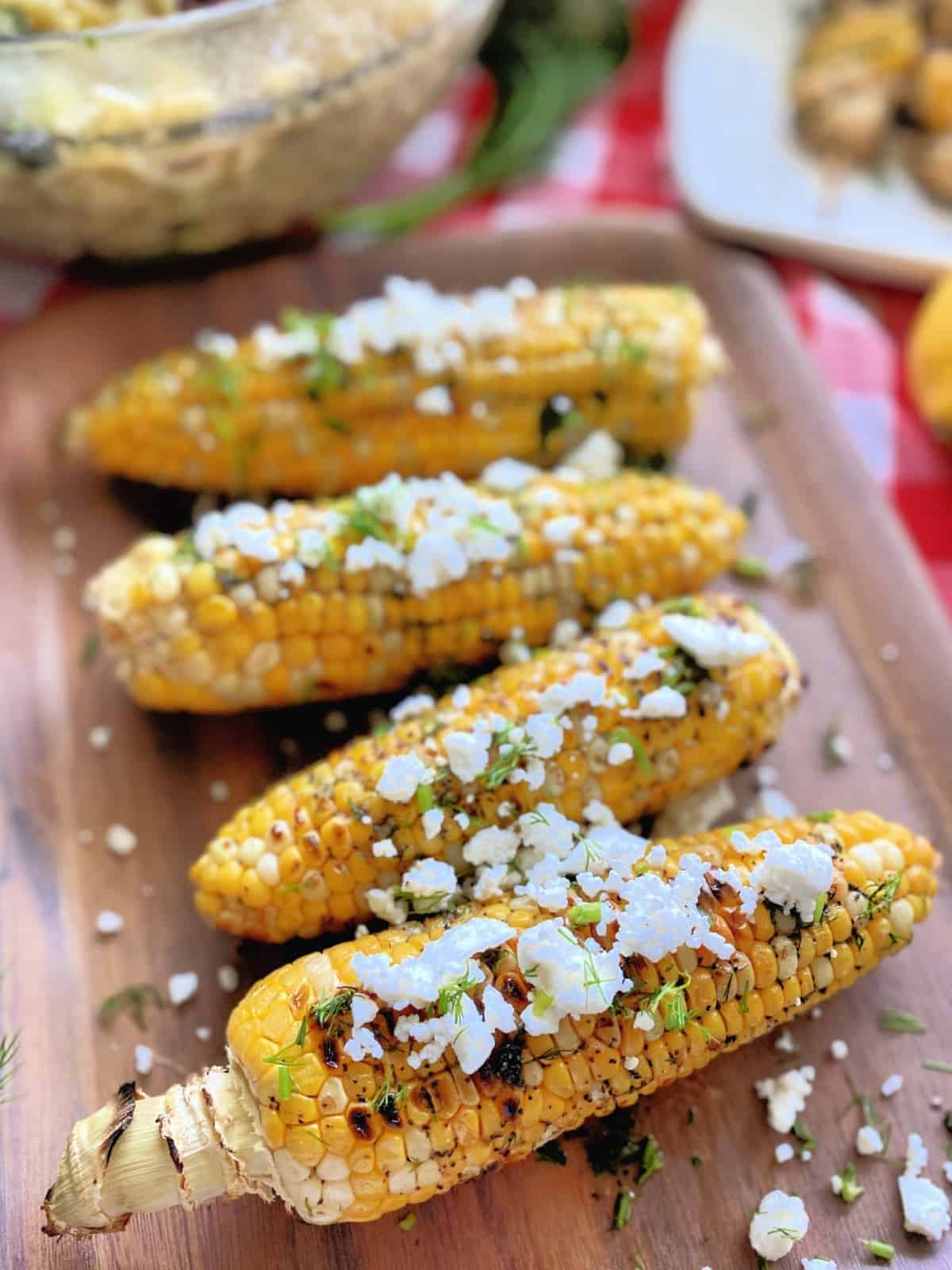 Greek Dill and Butter Grilled Corns on the Cob on a wooden tray.