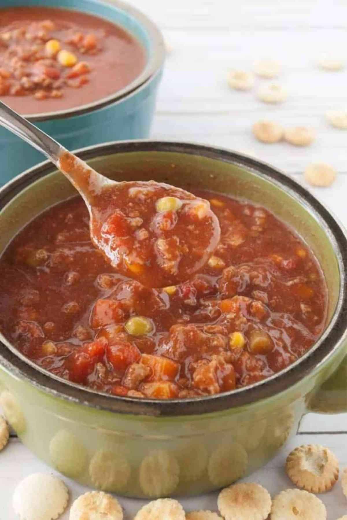 Slow Cooker Vegetable Beef Soup in a green bowl picked with a spoon..