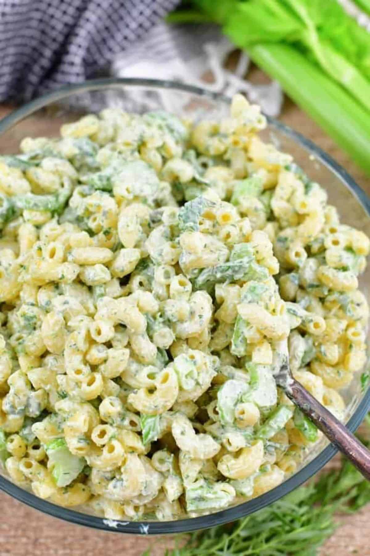 Green Goddess Macaroni Salad in a glass bowl with a spoon.