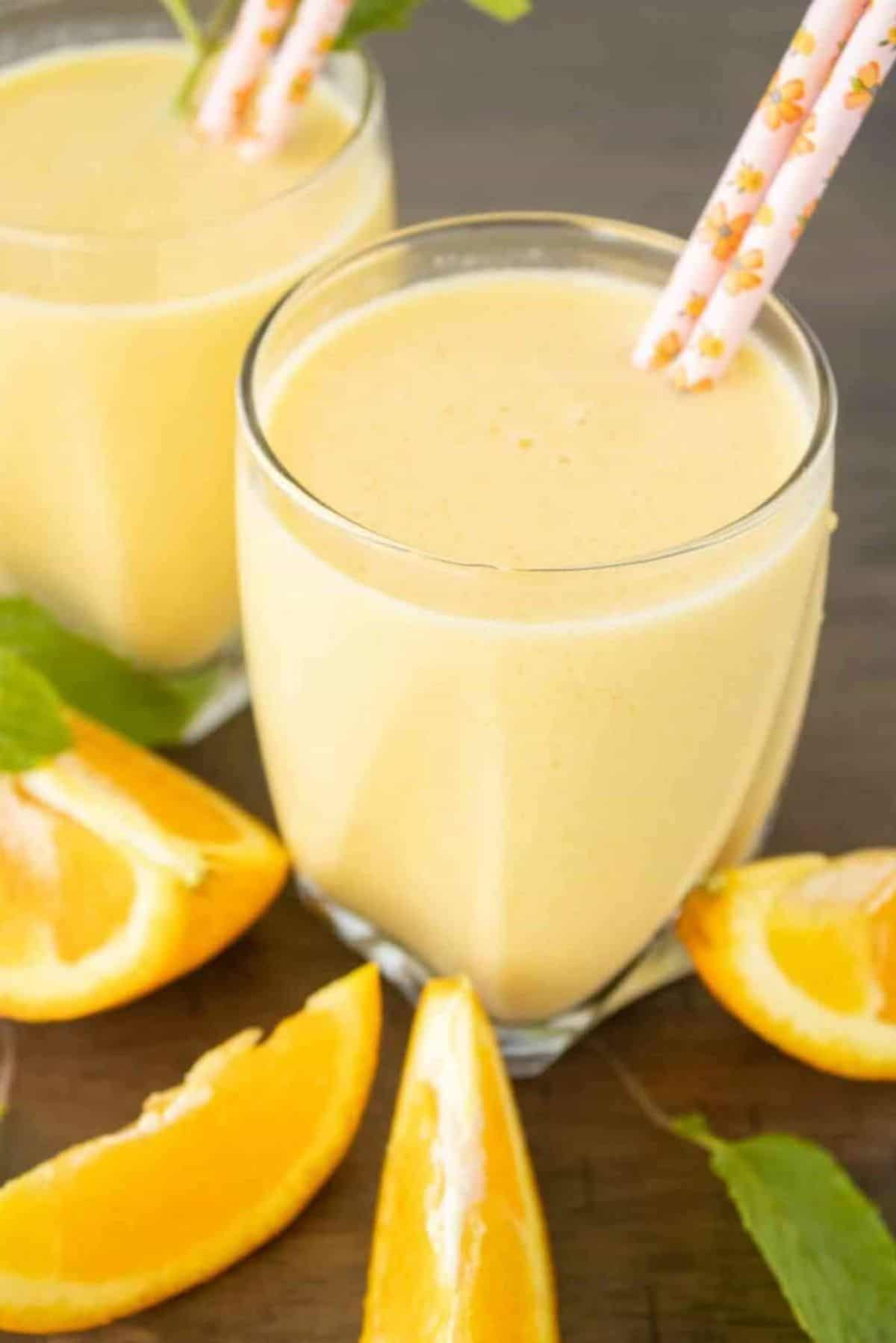 Orange Julius drink in a glass with two straws.