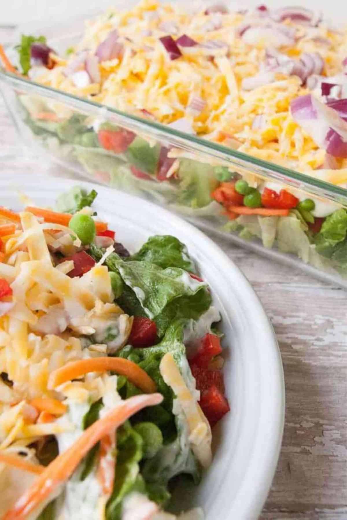 Overnight Layered Green Salad on a white plate and in a glass casserole.