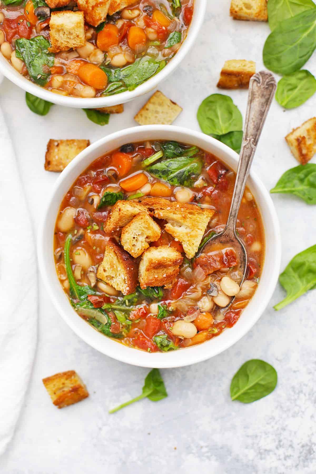 Sun-dried Tomato White Bean Soup in a white bowl with a spoon.