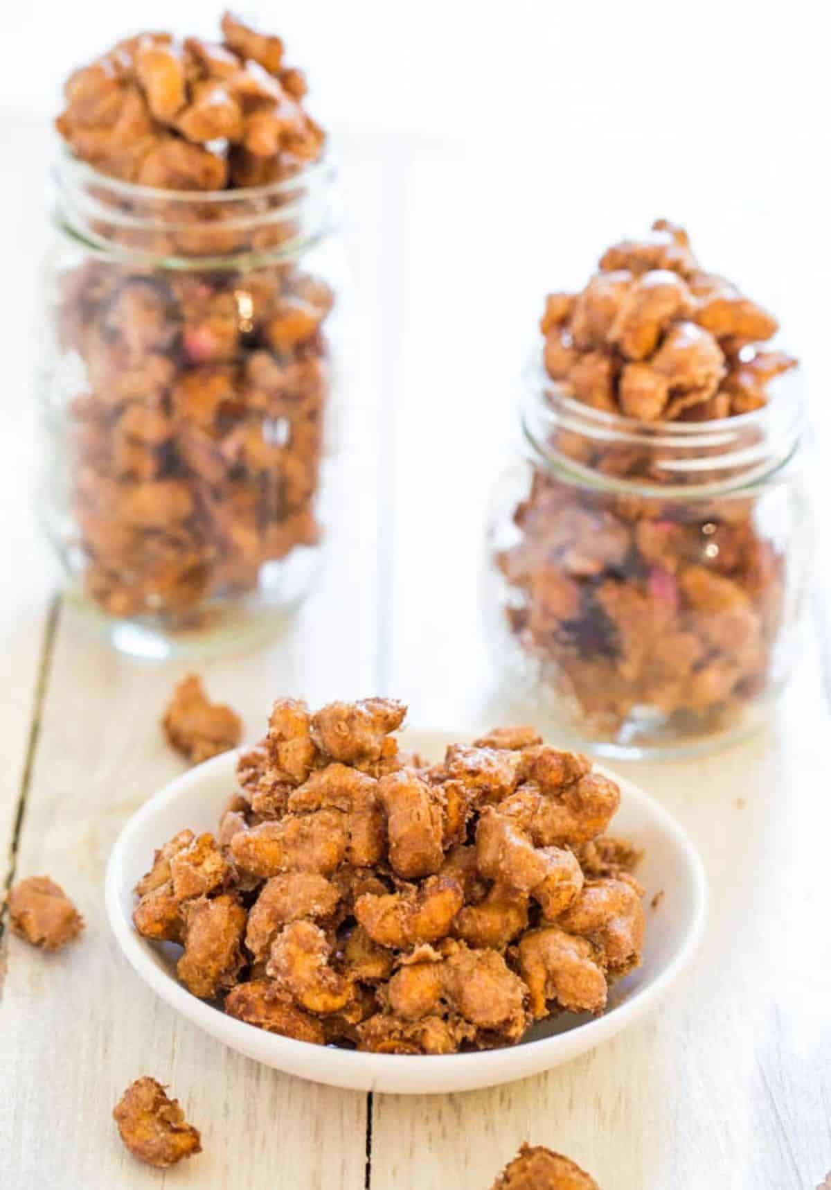 Cinnamon Sugar Candied Cashews in a white bowl and two glass jars.