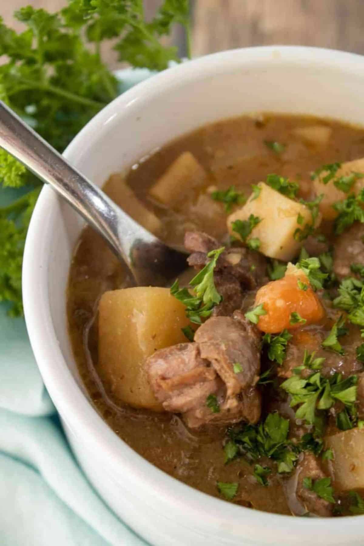 Slow Cooker Beef Stew in a white bowl with a spoon.