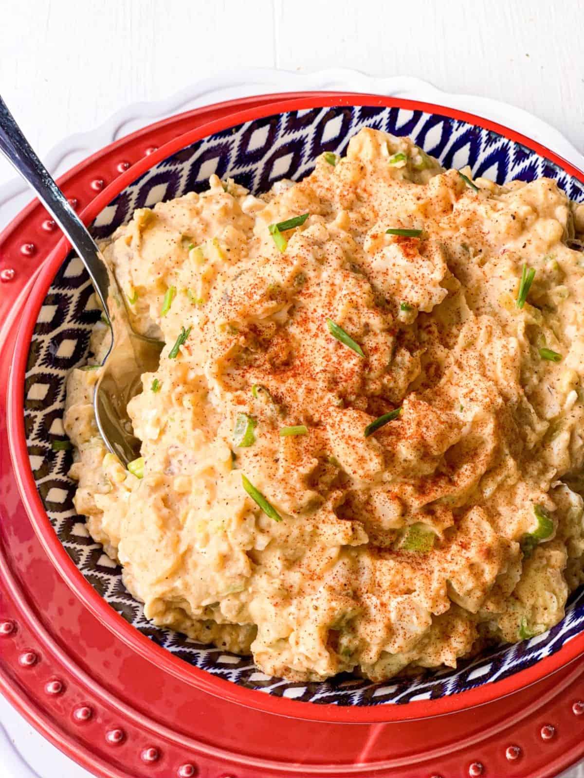 Creole Potato Salad in a festive bowl with a spoon.