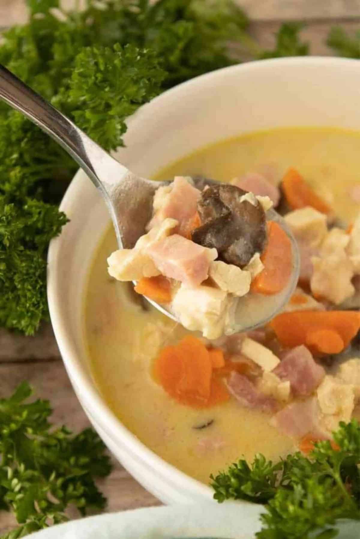 Chicken Cordon Bleu Soup in a white bowl picked with a spoon.