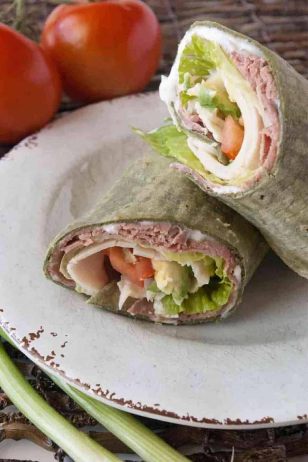 Two Roast Beef Turkey Avocado Wraps on a white plate.