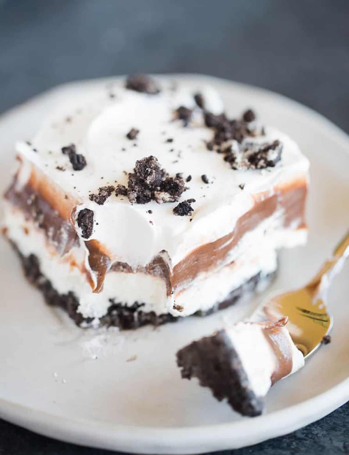 A piece of Oreo Layer Cake on a white plate with a fork.