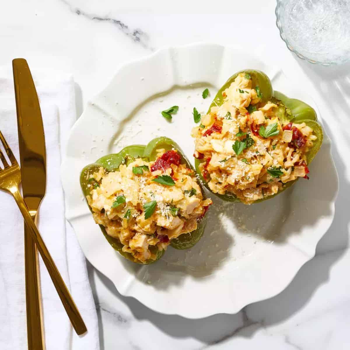 Chicken & Rice Stuffed Peppers with Sun-dried Tomato Cream Sauce on a white plate.