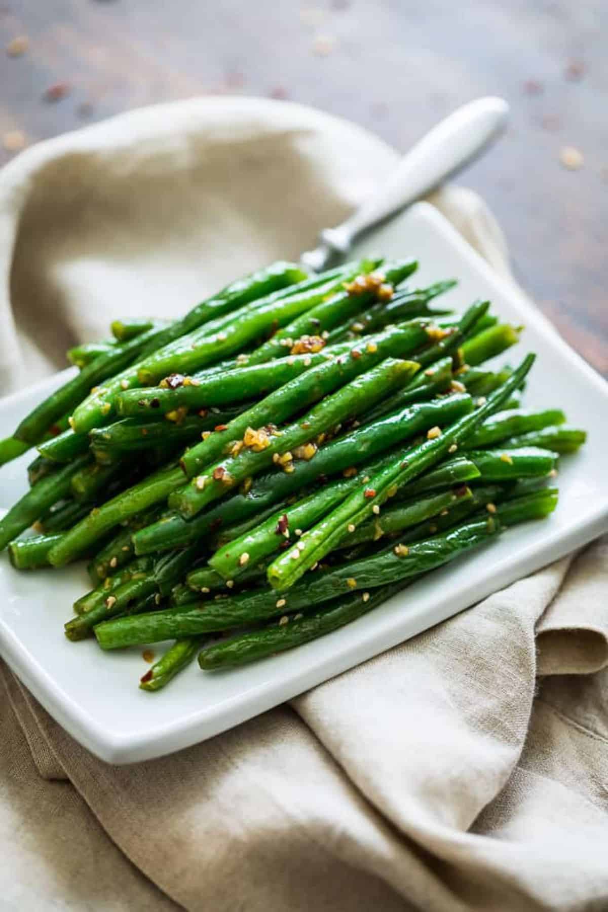 Healthy Sesame Ginger Glazed Green Beans on a white tray.