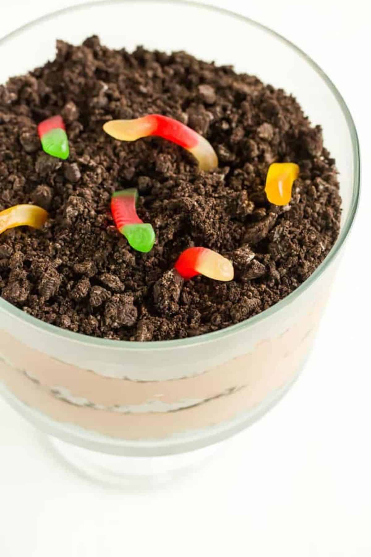 Dirt Dessert with gummy worms in a glass cup.