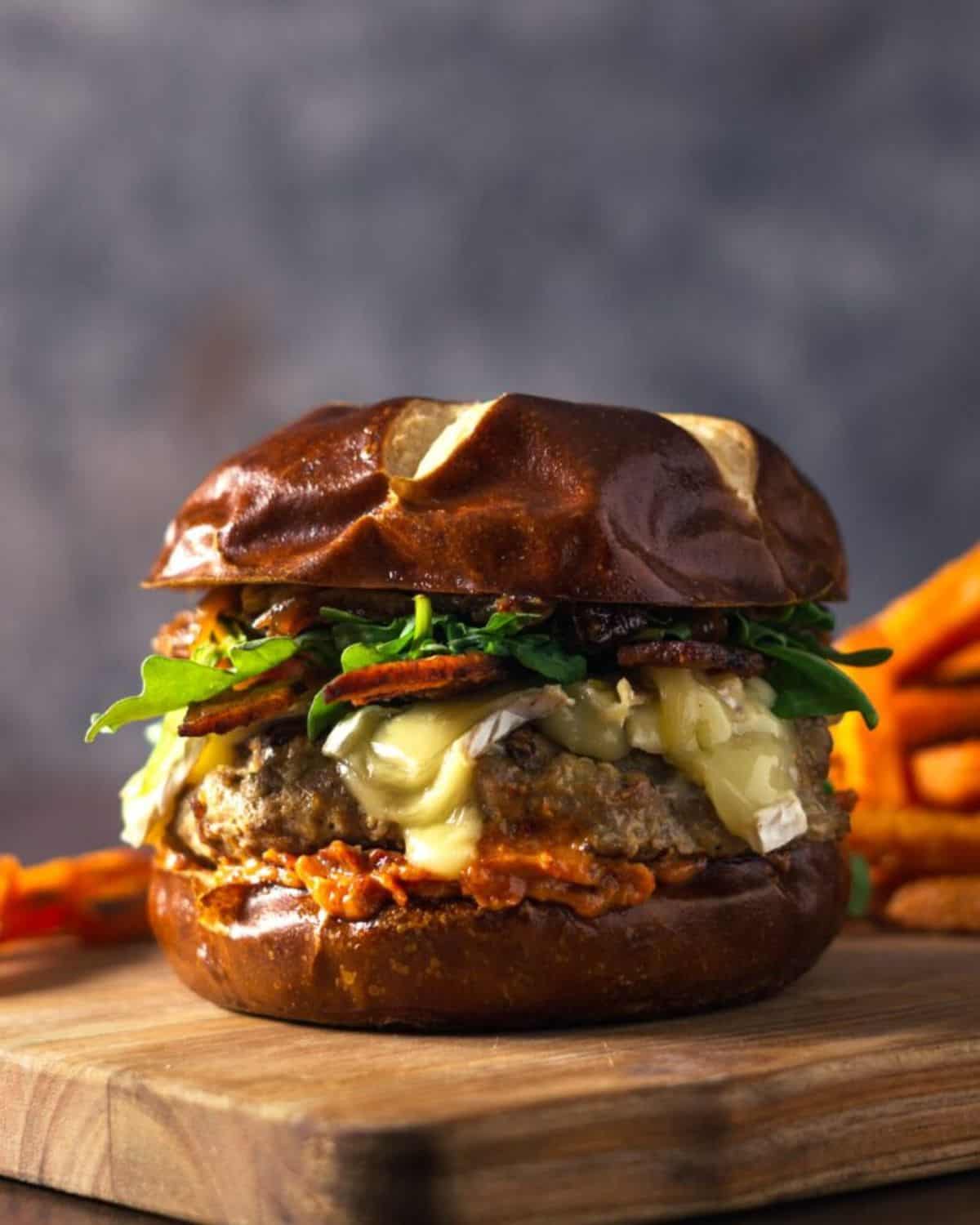 Turkey Burger with Caramelized Onions, Brie, and Sun-dried Tomato Mayo on a wooden cutting board.