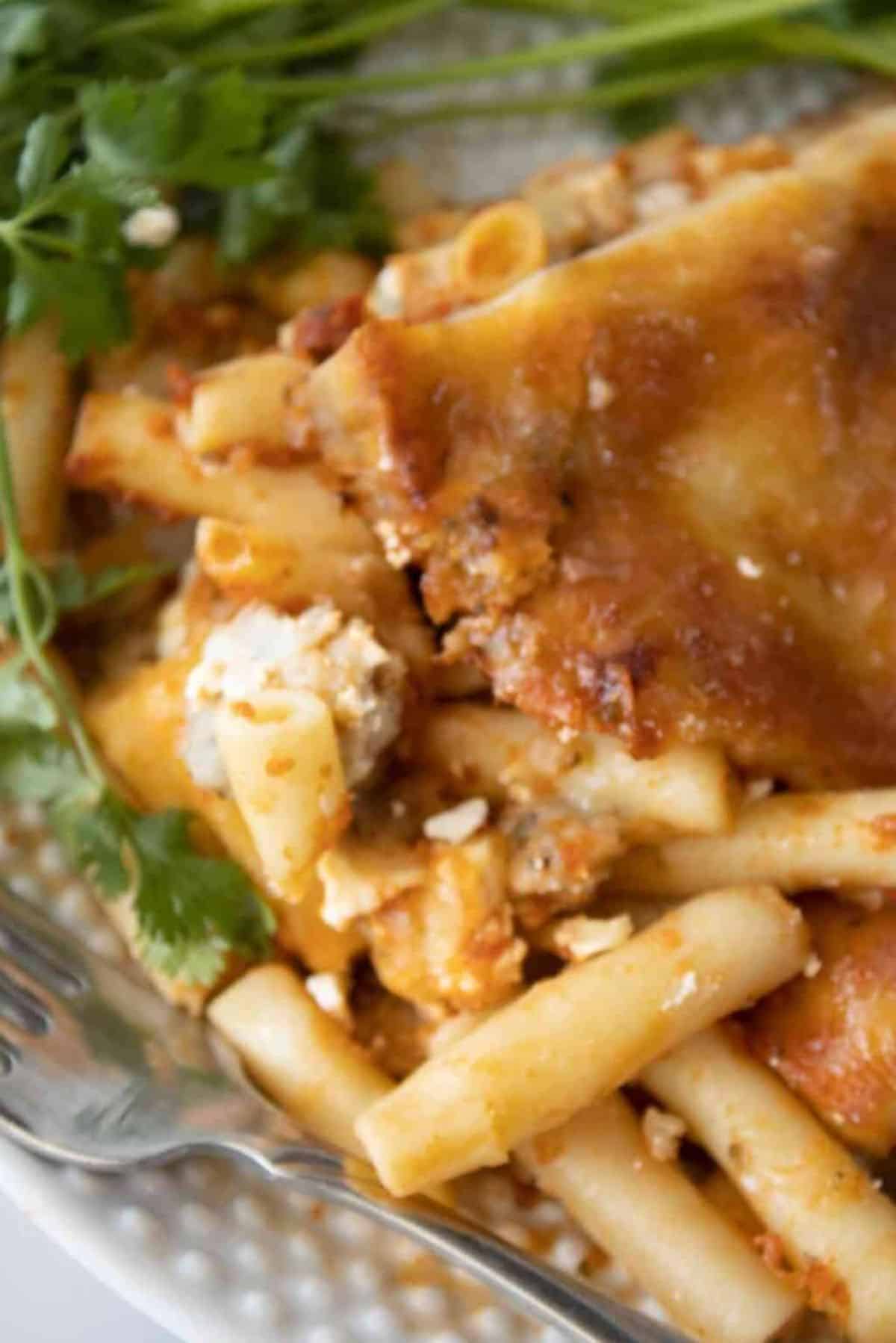 Deliicous Baked Ziti with Sausage on a white plate with a fork.