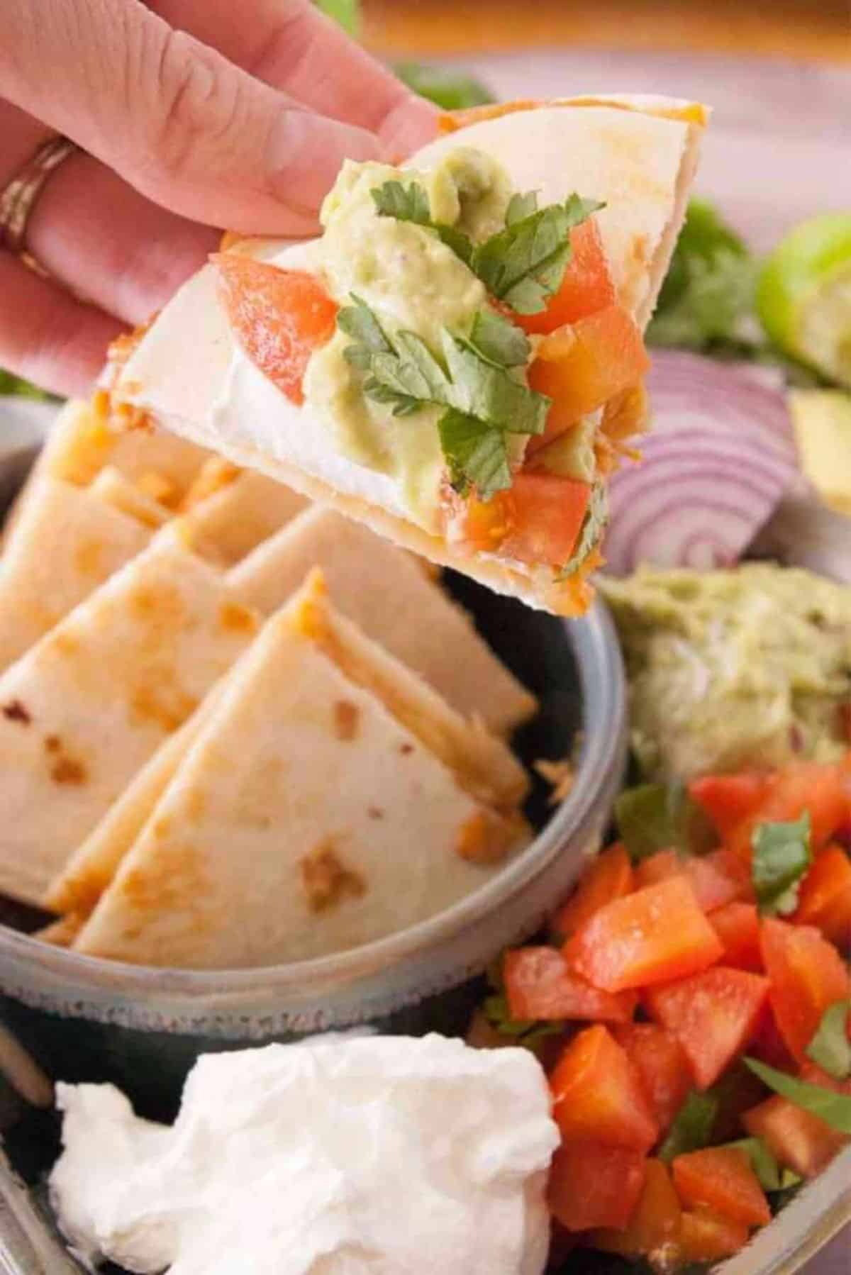 Tasty Buffalo Chicken Quesadillas on a tray, one held by hand.