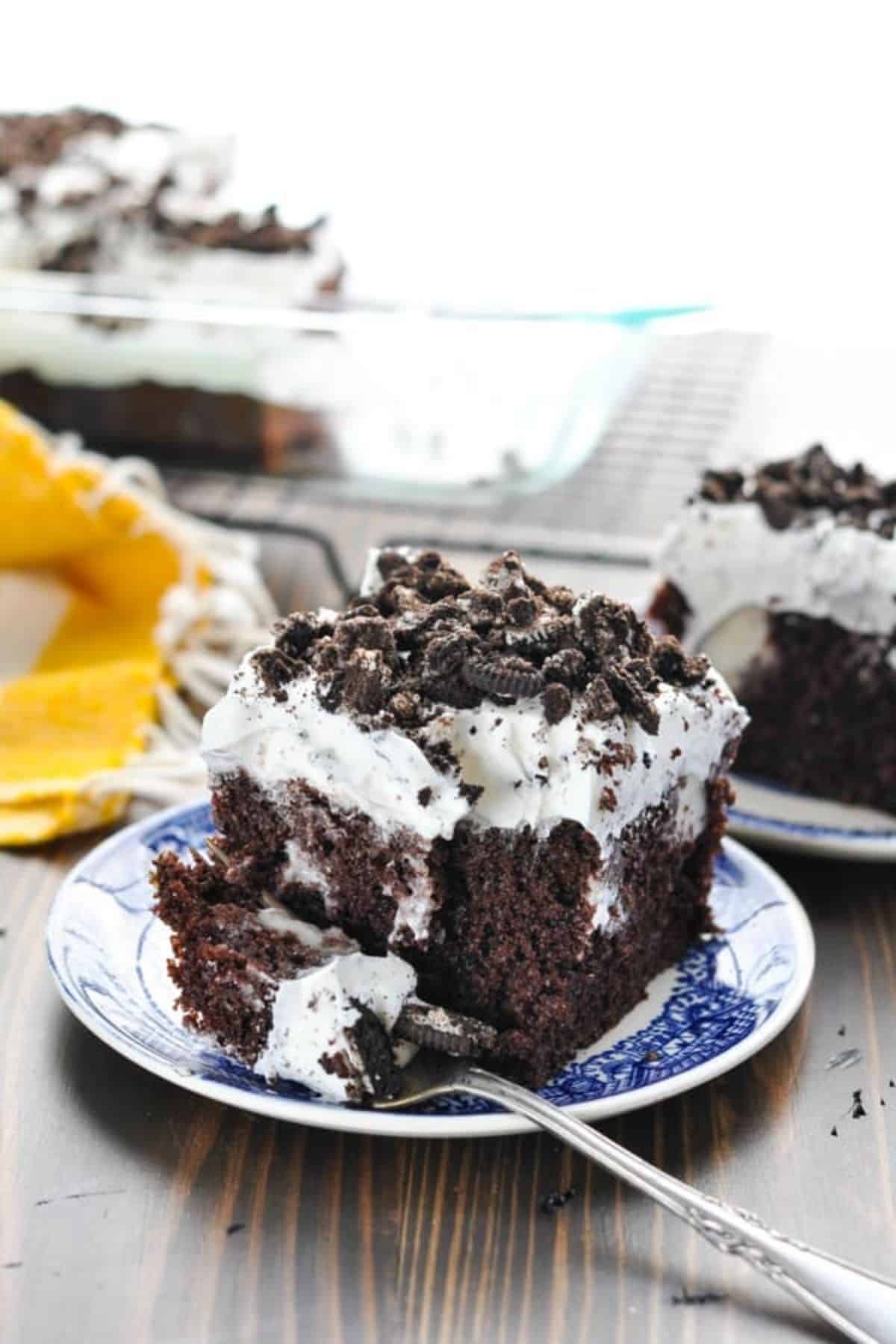 A piece of Cookies n' Cream Oreo Cake on a small plate with a fork.