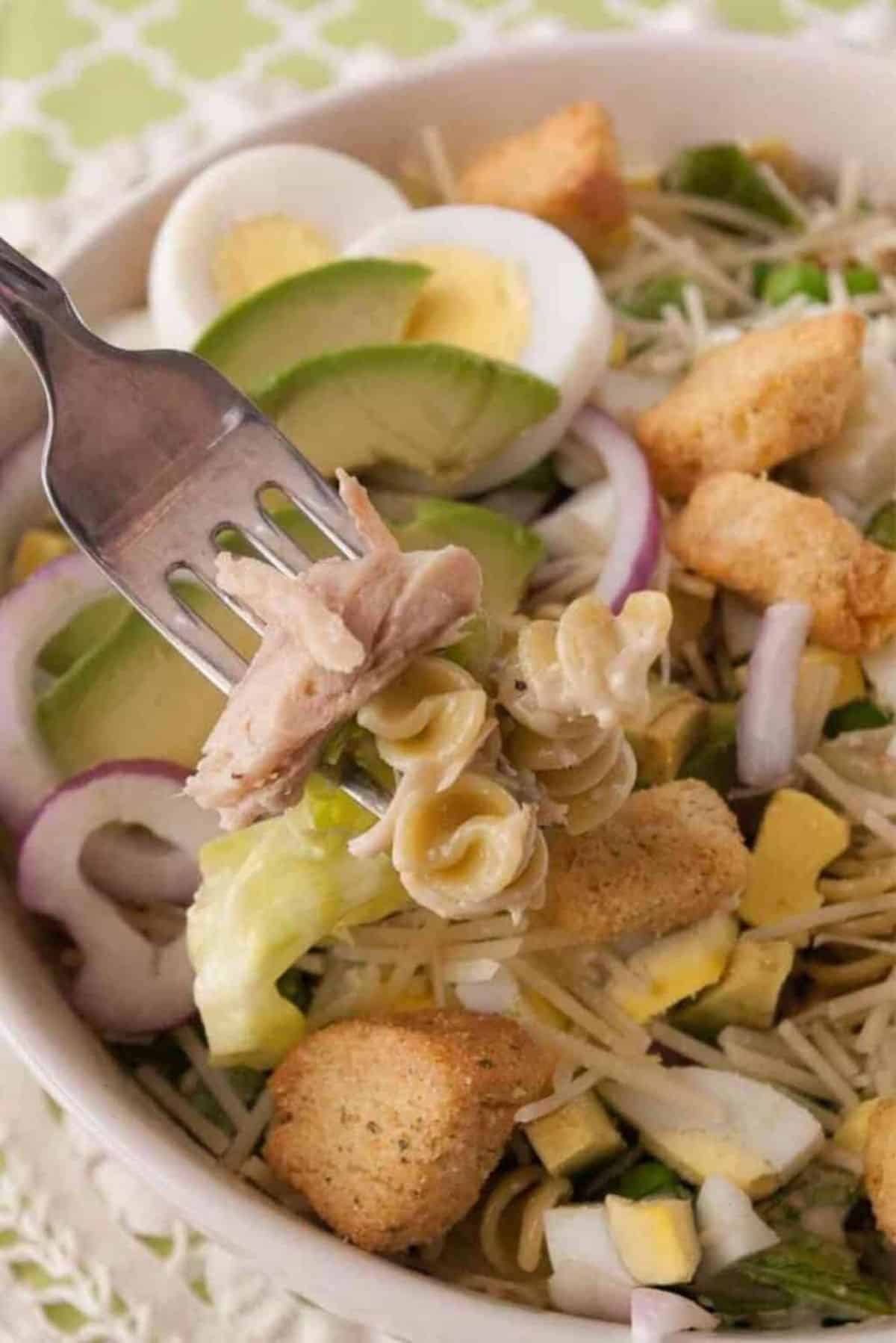 Delicious Best Chicken Cesar Pasta Salad in a white bowl with a fork.