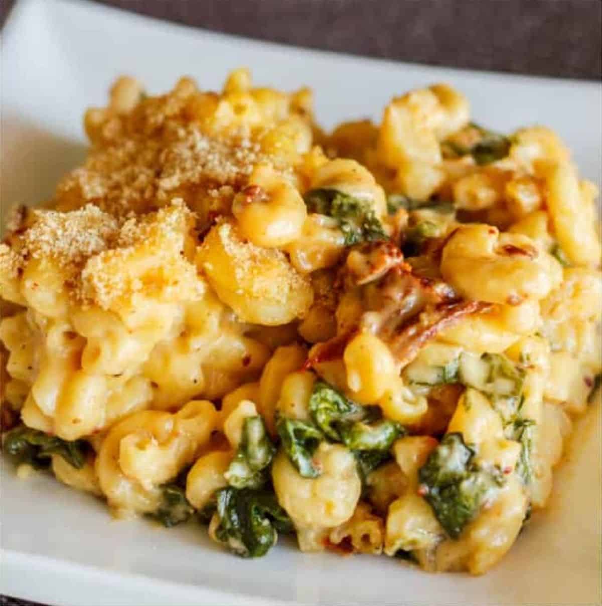 Macaroni and Cheese with Sun-dried Tomatoes and Spinach on a white plate.