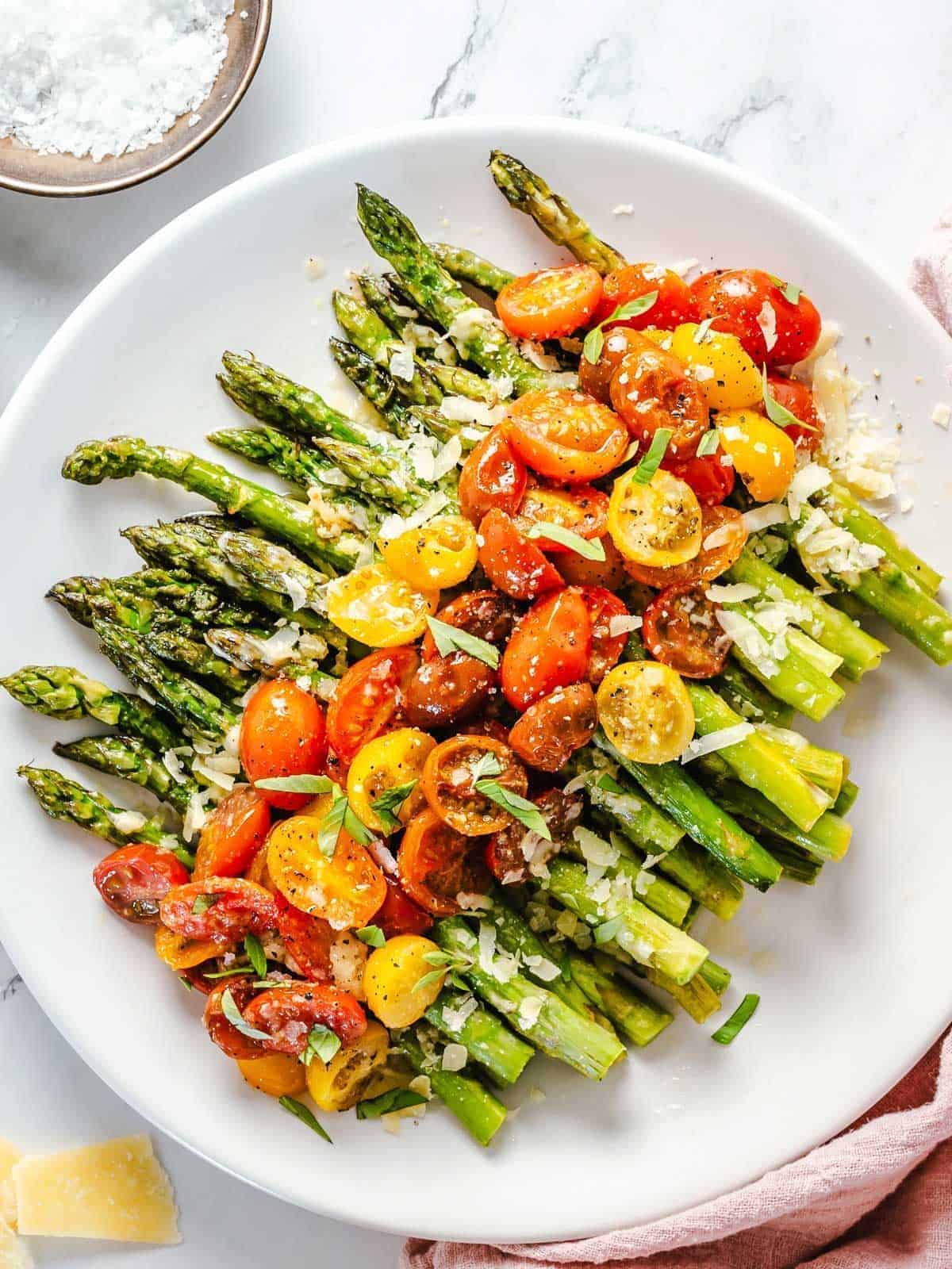Healthy Cheesy Asparagus with Tomatoes on a white plate.