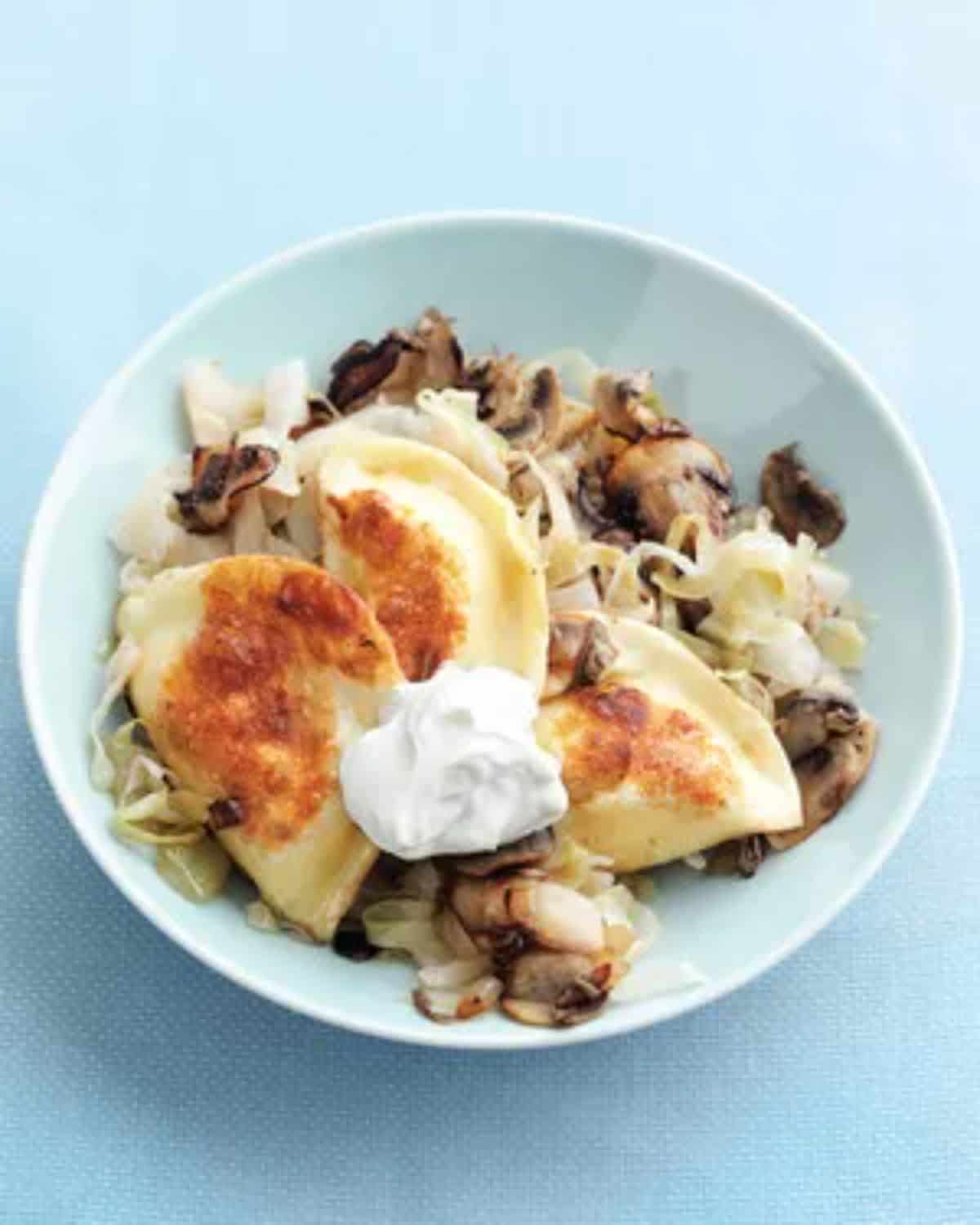 Tasty Pierogi with Sauerkraut and Mushrooms on a blue plate.