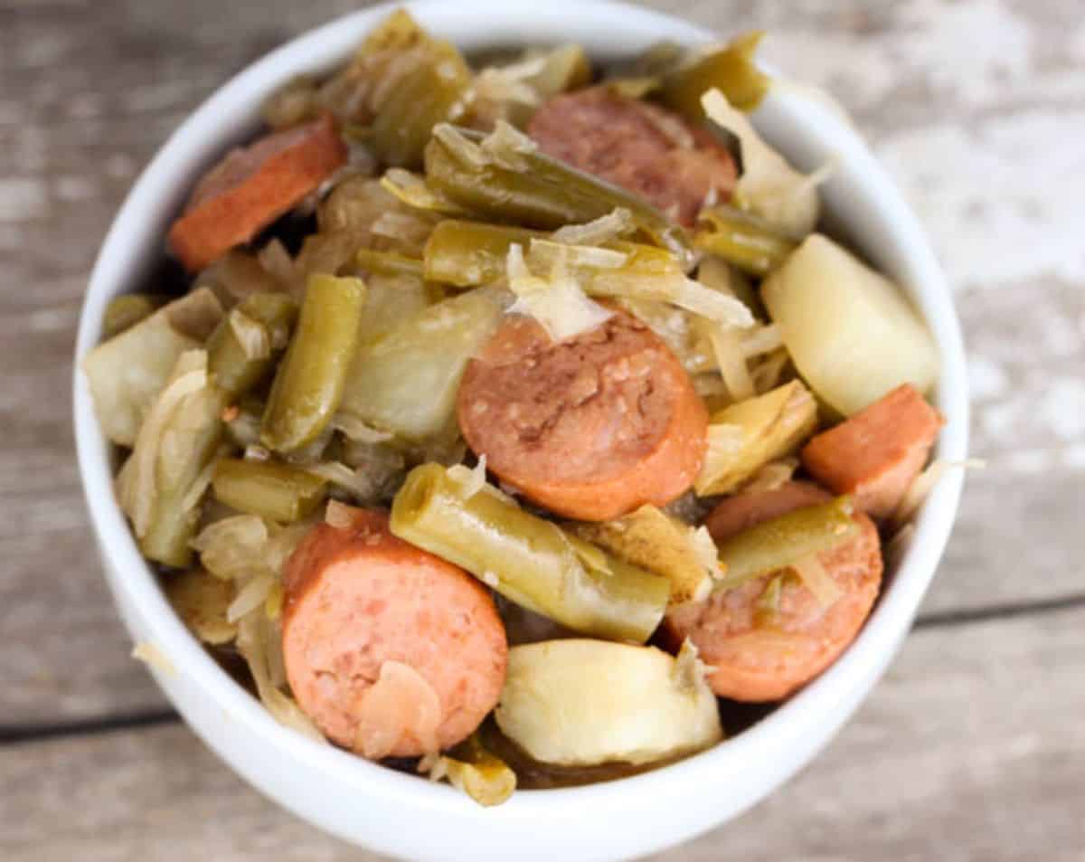 Smoked Sausage Sauerkraut with Potatoes and Green Beans in a white bowl.