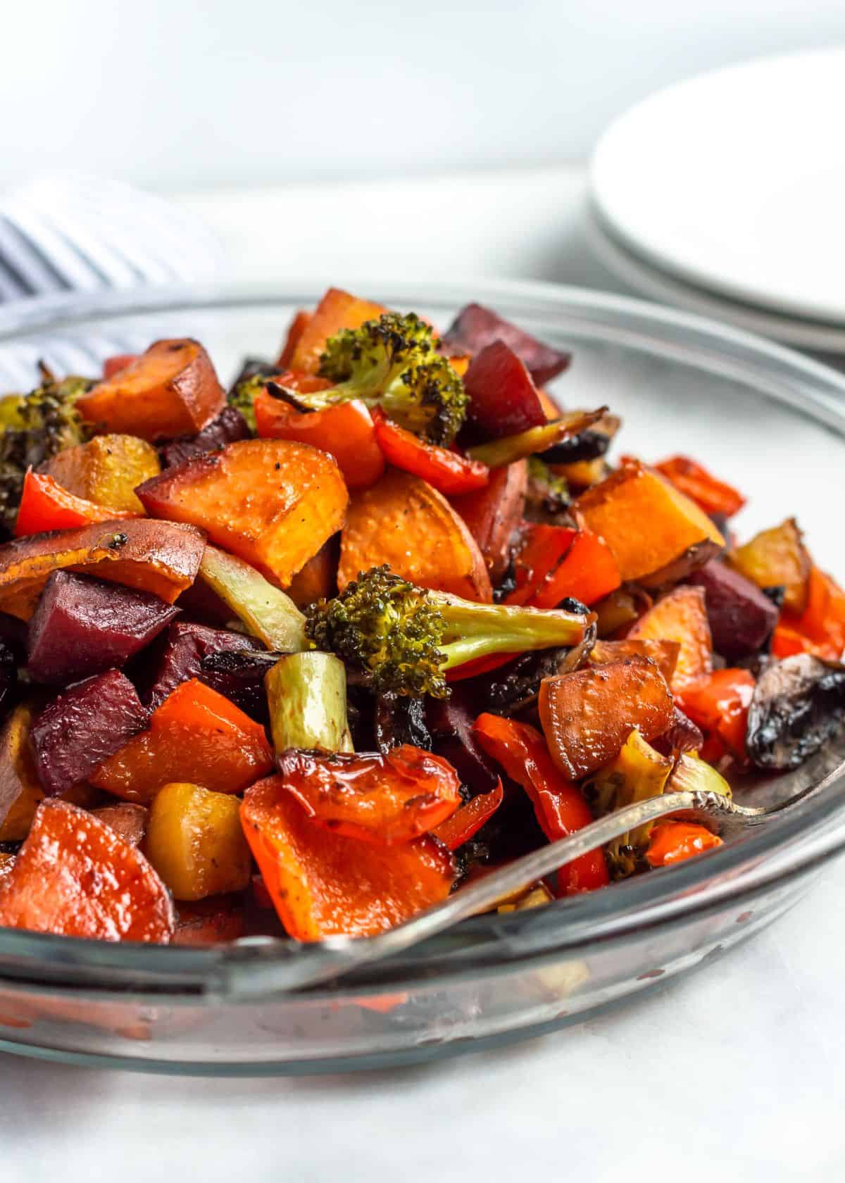 Deliicous Balsamic Honey Roasted Vegetables in a glass bowl with a spoon.