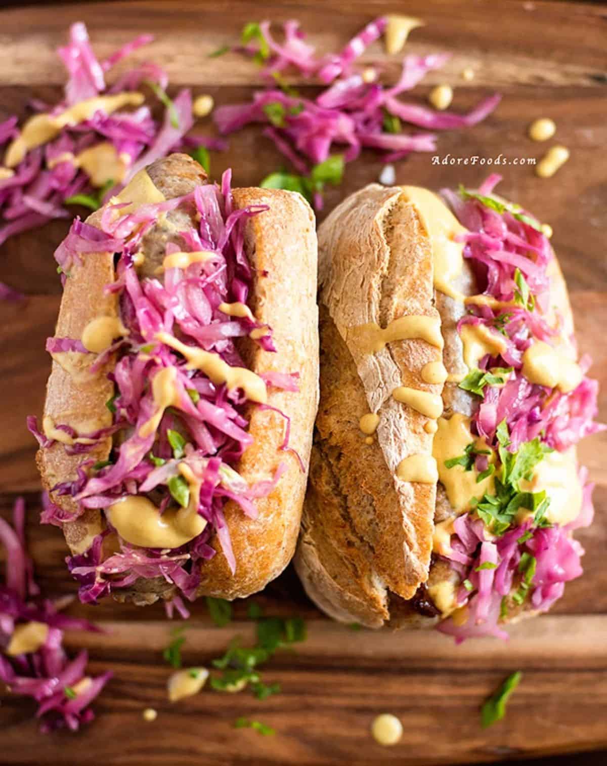 Two German Bratwurst Hot Dogs With Red Cabbage Sauerkraut on a wooden table.