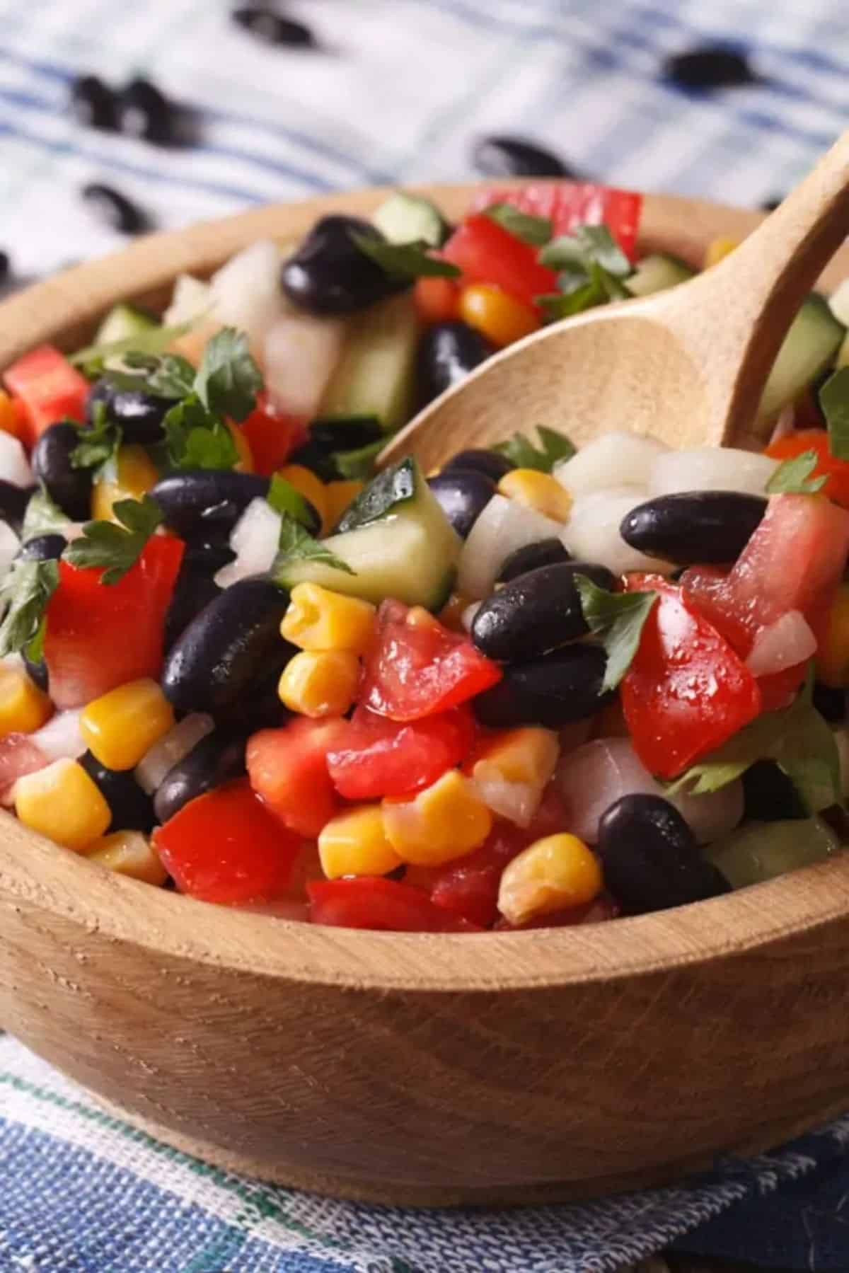 Healthy High Protein Mexican Bean Salad in a wooden bowl with a wooden spoon.