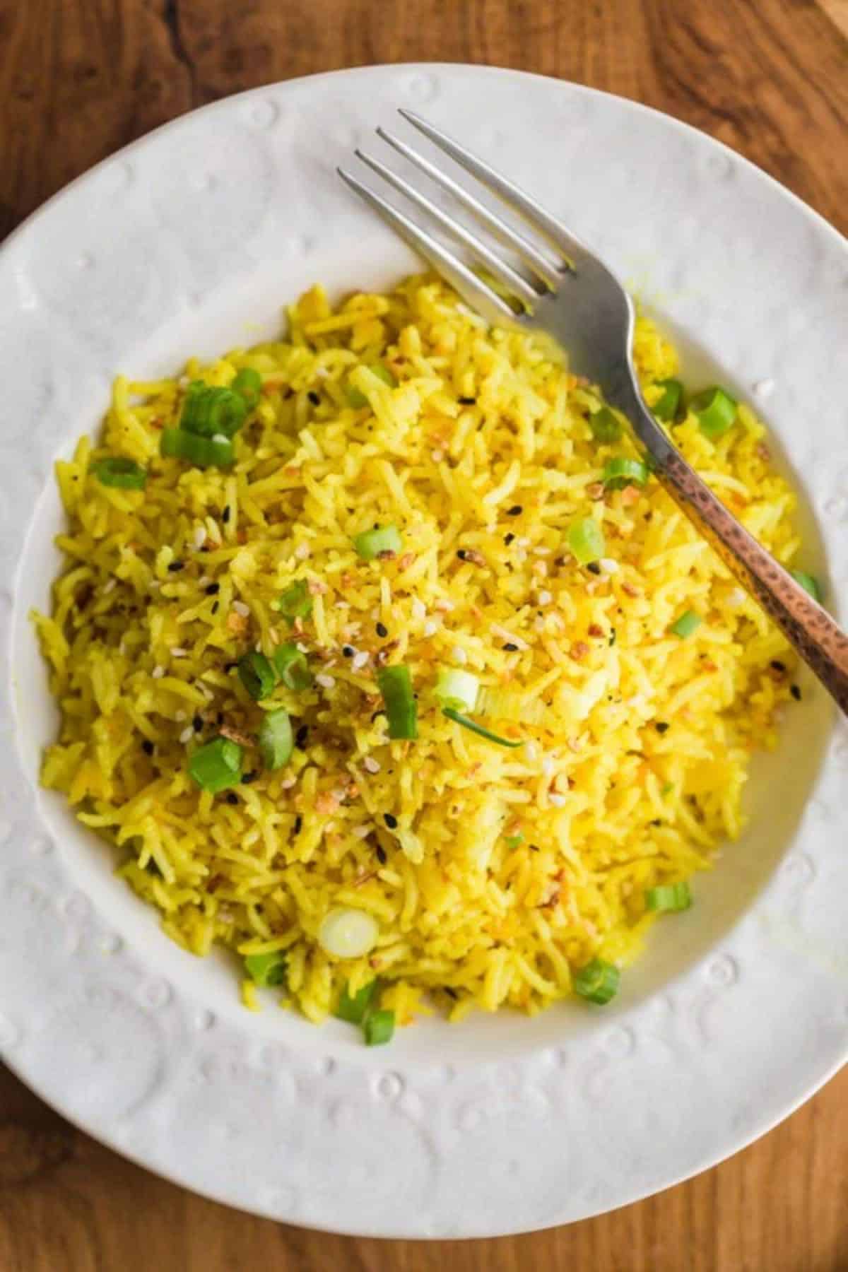 Healthy Turmeric Lemon Rice on a white plate with a fork.