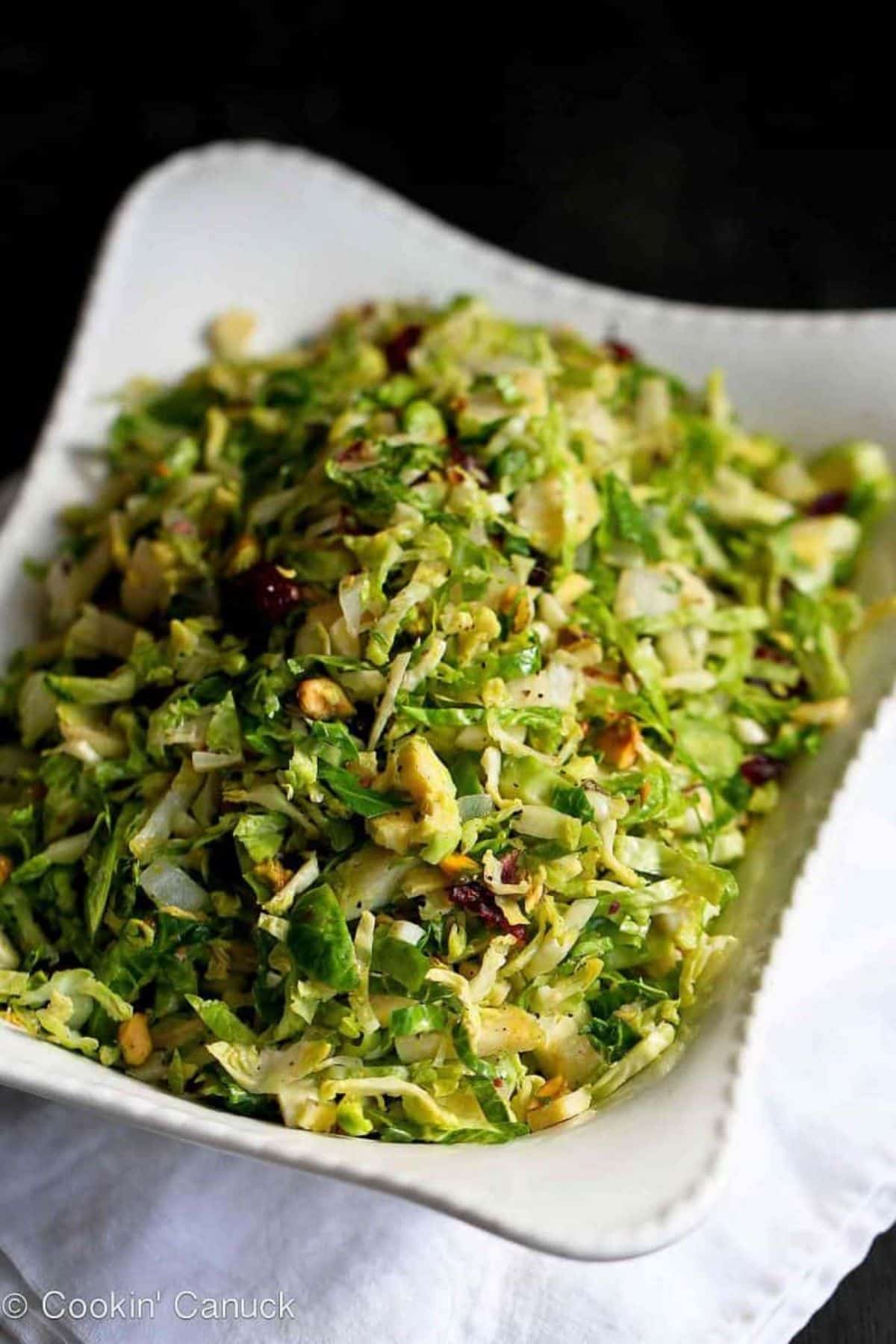 Healthy Shredded Brussels Sprouts with Pistachios, Cranberries & Parmesan in a white bowl.