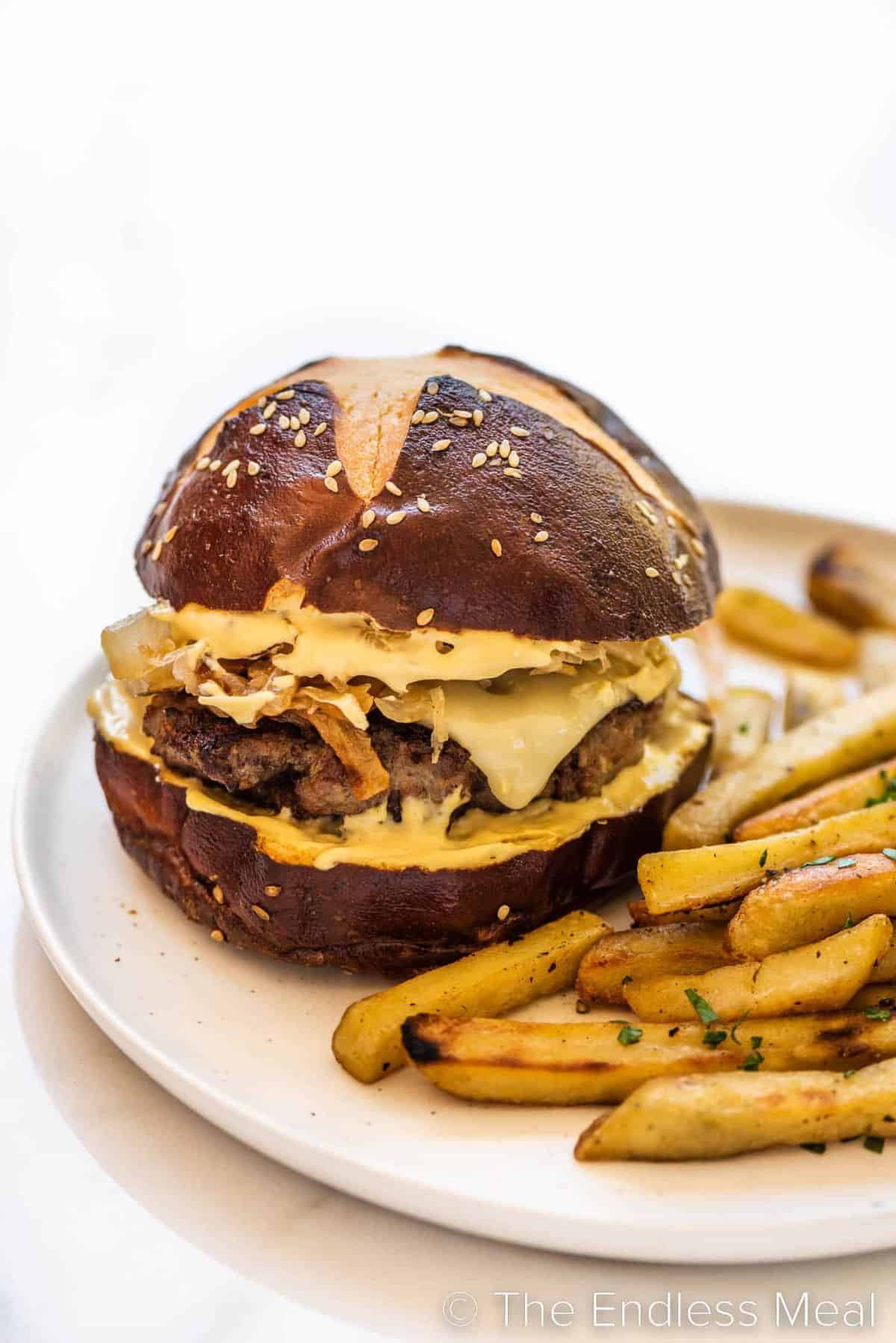 Bratwurst Burger With Onion Sauerkraut Topping with fries on a white tray.