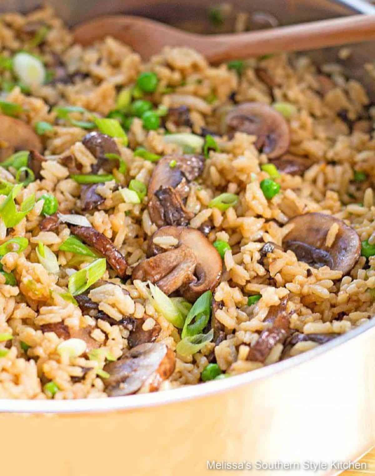 Delicious Teriyaki Rice Pilaf With Mushrooms and Peas in a skillet with a wooden spoon.