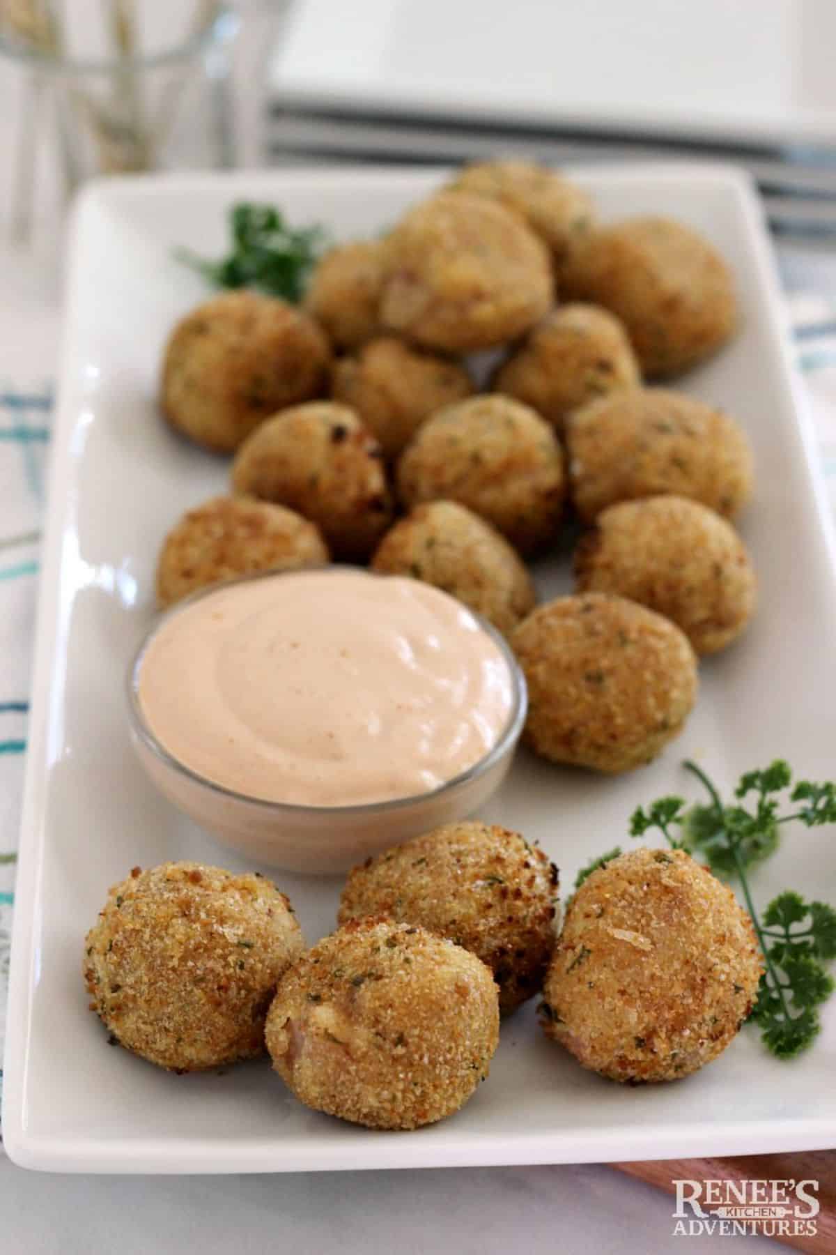 Crunchy Sauerkraut Balls with a bowl of dip on a white tray.