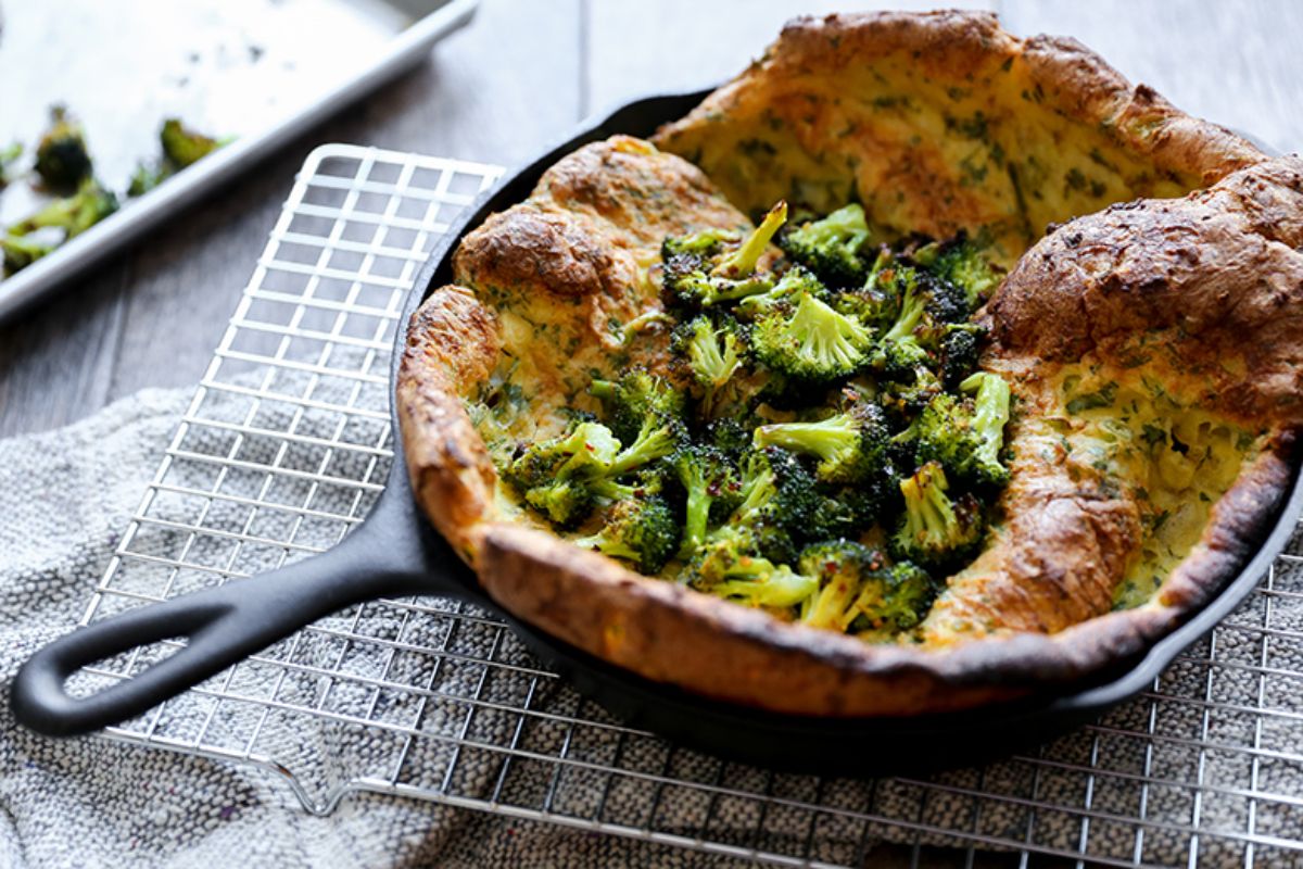 Delicious Savory Dutch Baby With Roasted Broccoli in a black skillet.