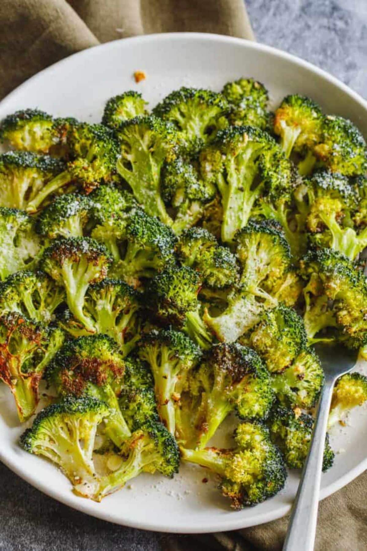 Healthy Oven-Roasted Broccolion a white plate with a fork.