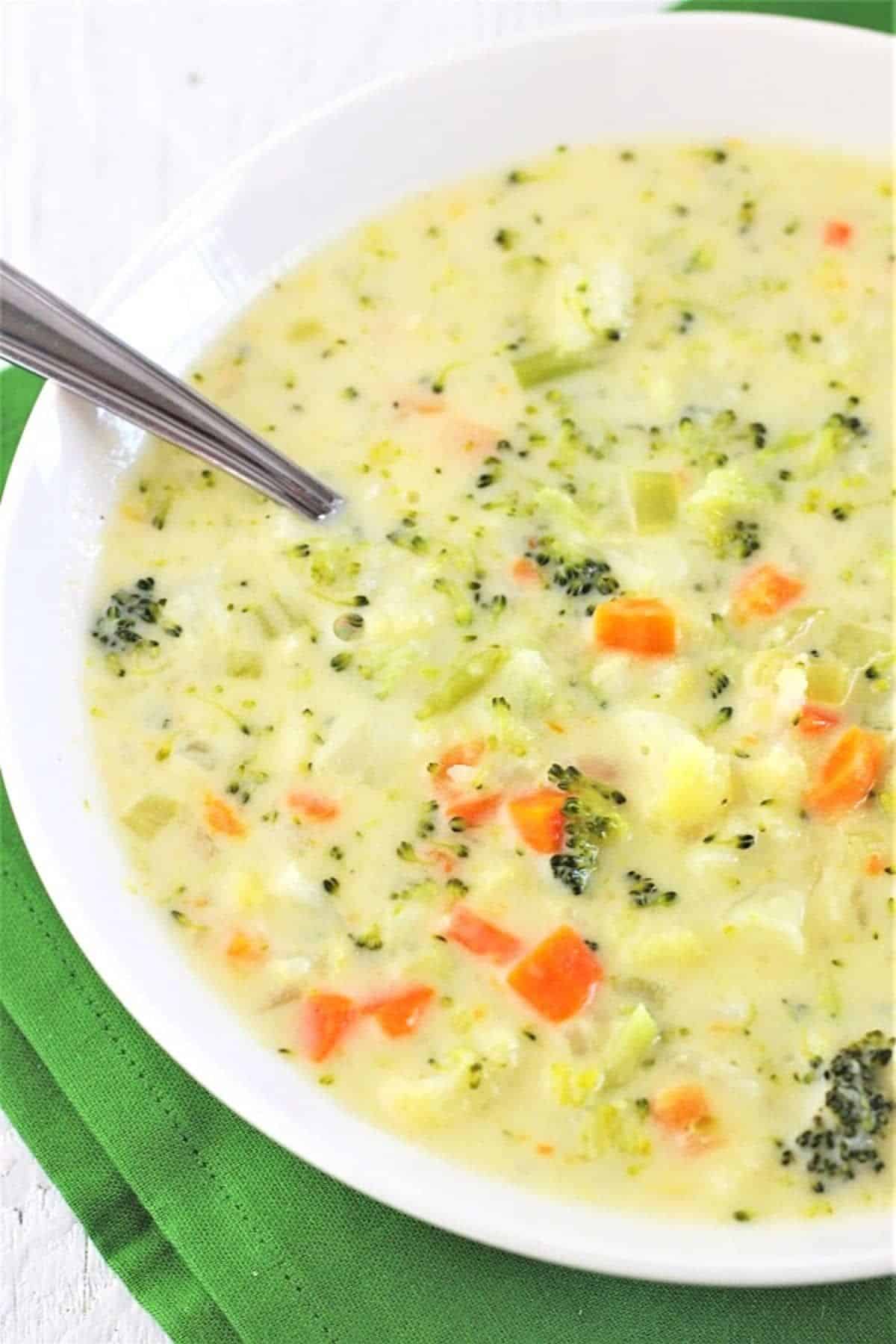 Creamy Broccoli and Cauliflower Cheese Soup in a white bowl with a spoon.