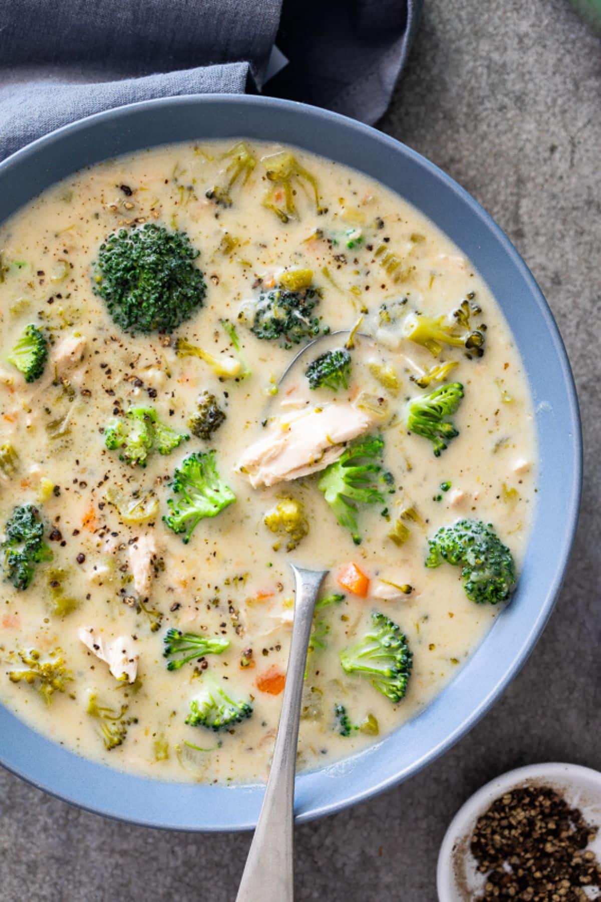 Creamy Healthy Chicken Broccoli Soupin a blue bowl with a spoon.